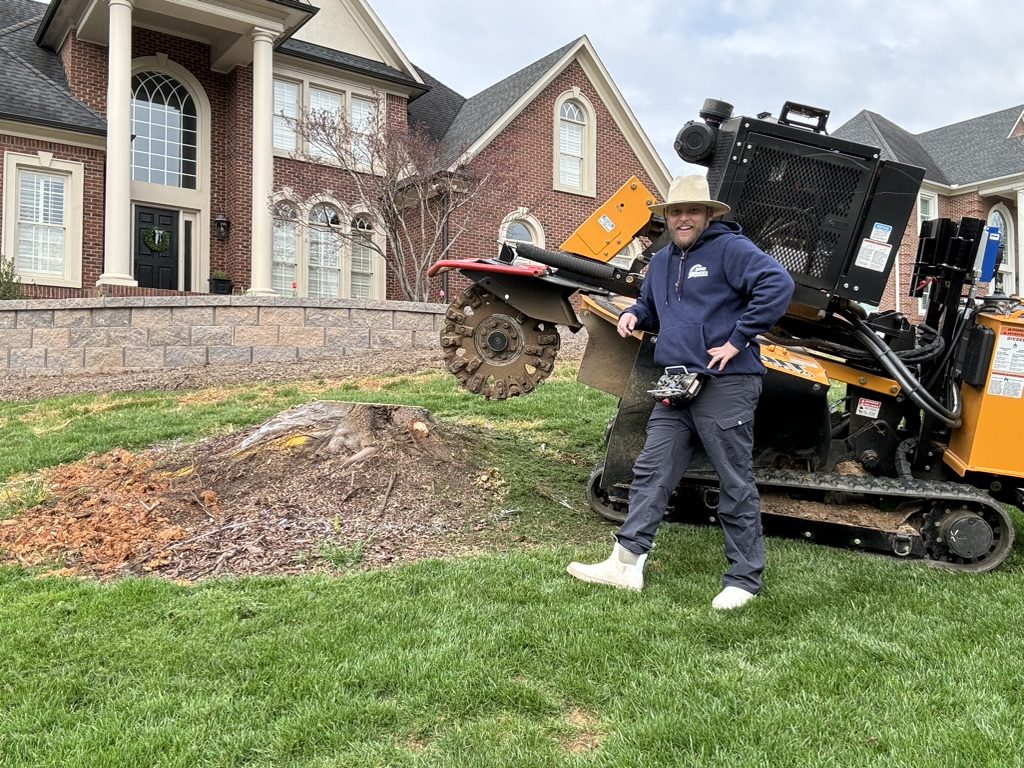 Brock Kothe, owner of Stump Busters, beside his tracked stump grinder and a partly ground stump